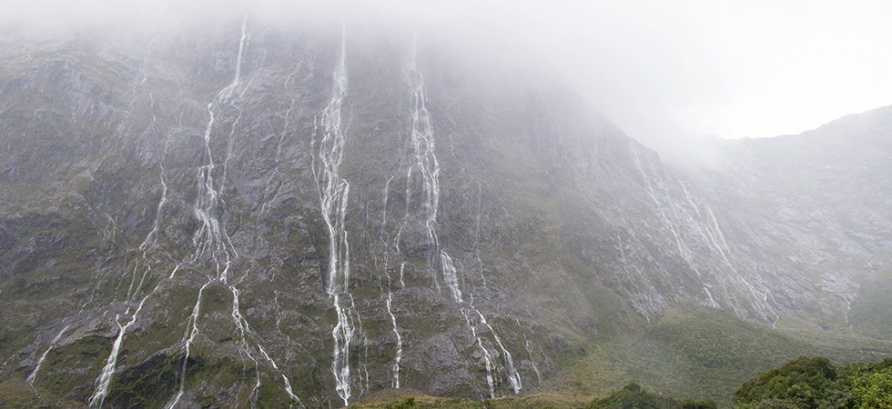 Misty granite mountain with waterfalls streaming down it